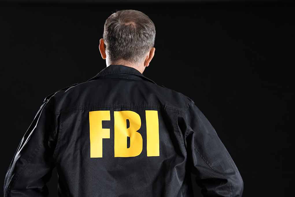 Man wearing FBI jacket, facing away.