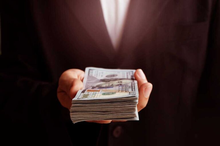 Hand holding a stack of US dollars.