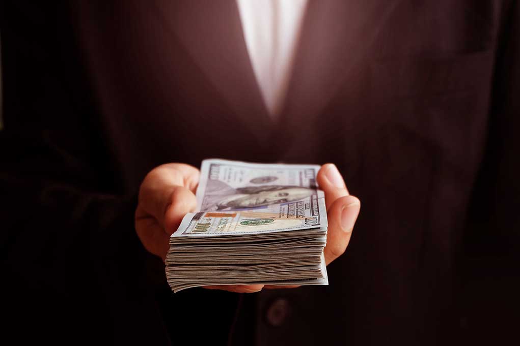 Hand holding a stack of US dollars.
