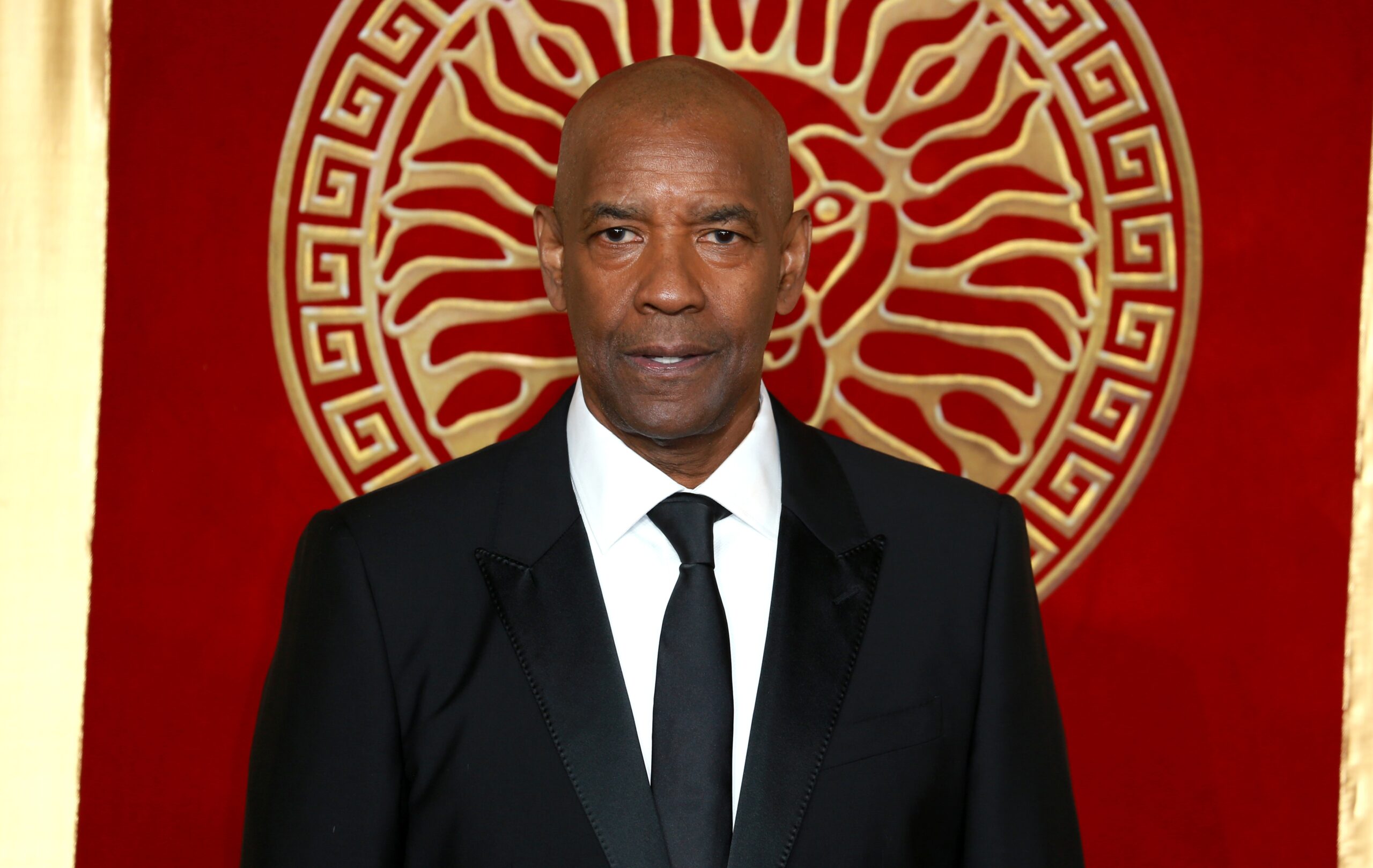 Man in suit standing before ornate red background