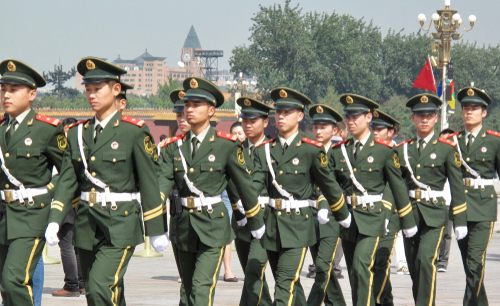 Soldiers in green uniforms march in formation outdoors.