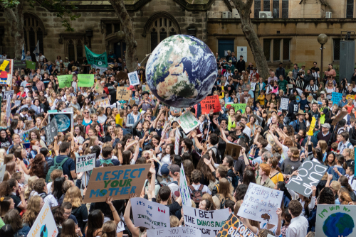Large climate change protest with many signs and globe balloon.
