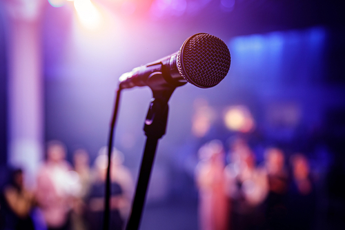 Microphone on stage with blurred audience in background.