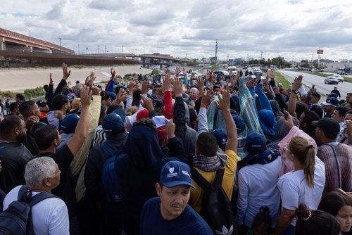 Crowd of people near a highway, arms raised.