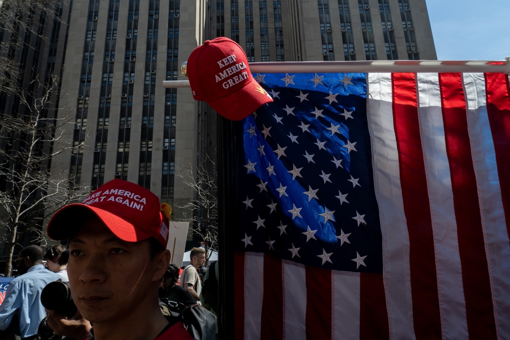 Man wearing red cap near American flag outdoors