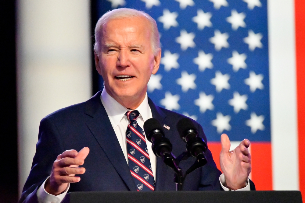 Man speaking at podium in front of flag