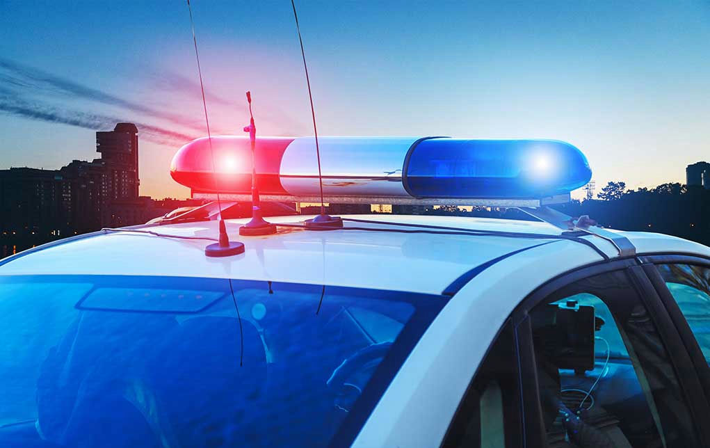 Police car with lights flashing at dusk.
