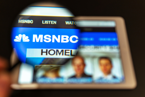 Magnifying glass over tablet displaying MSNBC homepage.