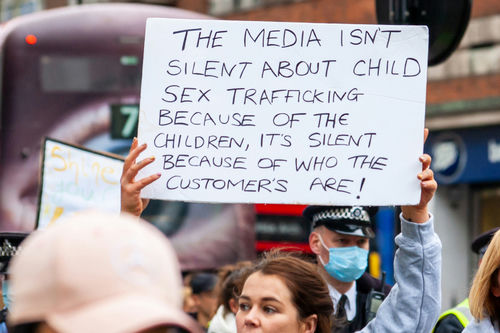 Protestor holding a sign about child sex trafficking in a crowd