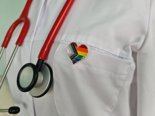 Doctor's coat with stethoscope and rainbow heart badge.