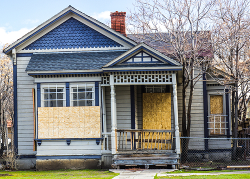 Boarded up house with fenced yard.