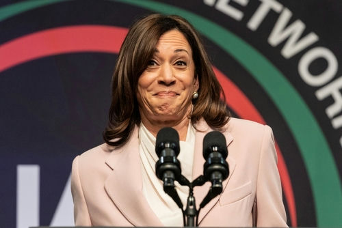 Kamala Harris speaks at event podium with two microphones.