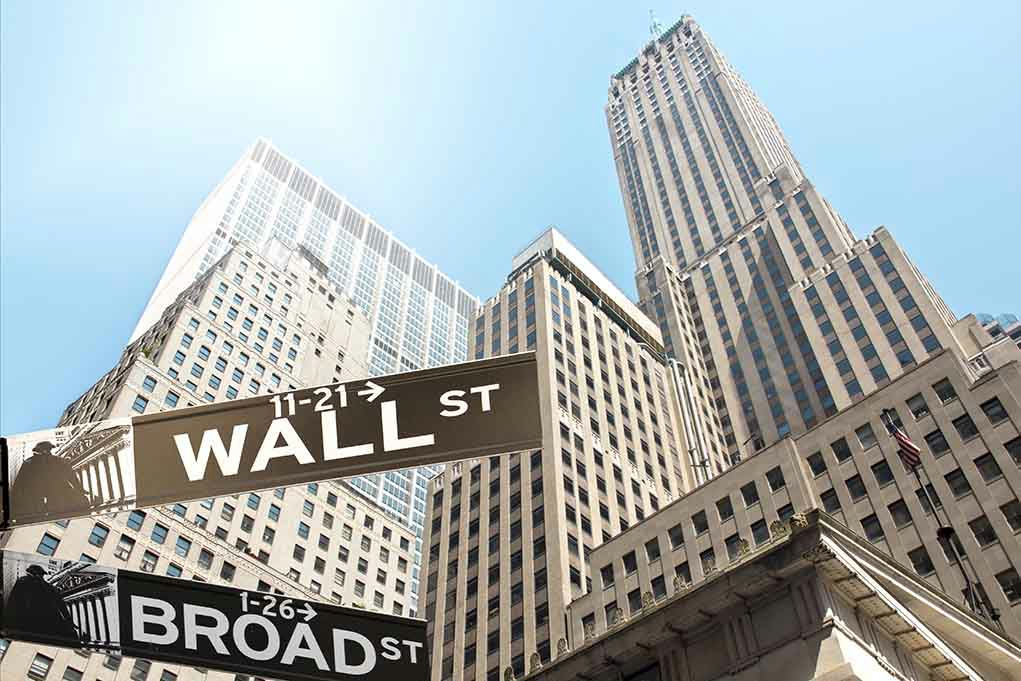 Wall Street and Broad Street signs, skyscrapers in background.