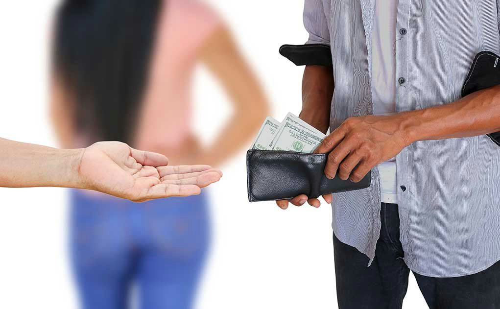 Hand holding out money towards another open hand.