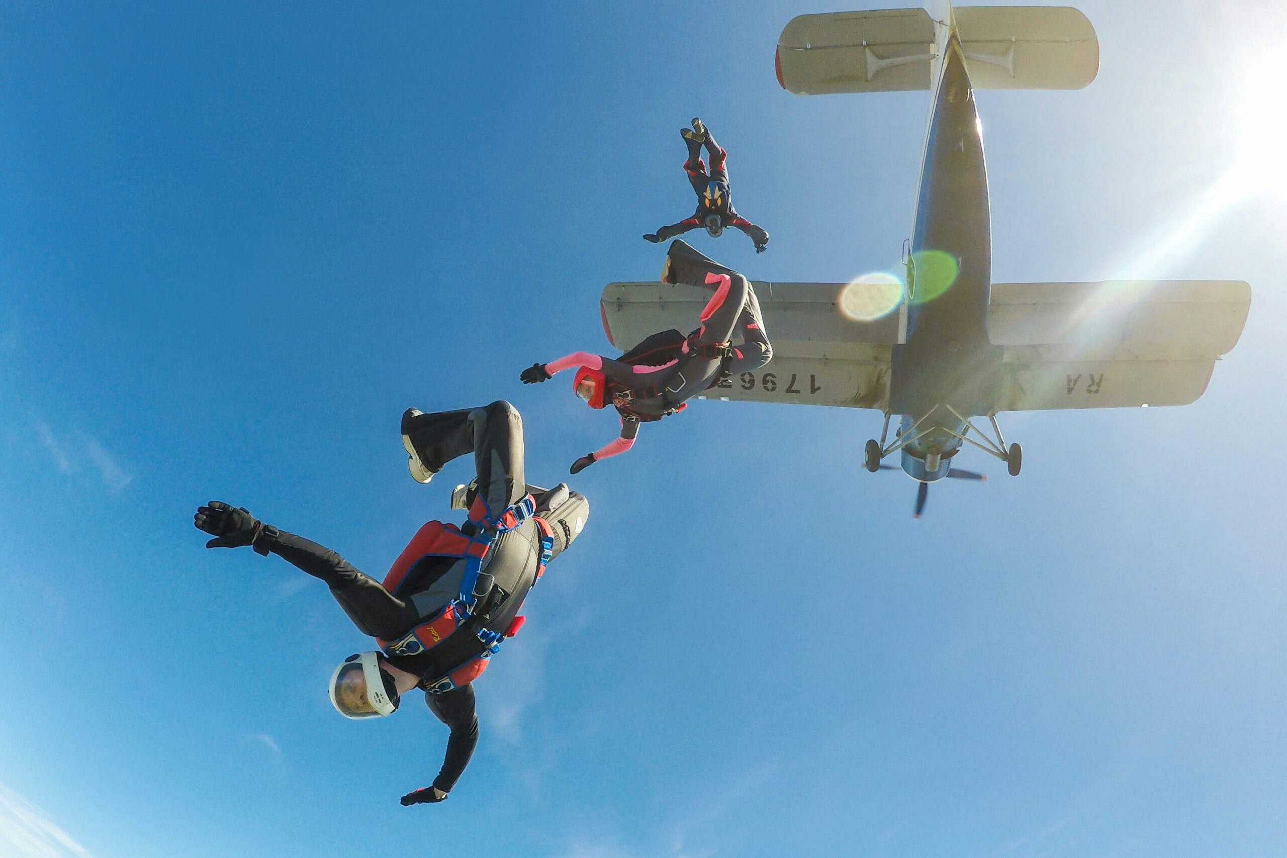 Skydivers freefalling below a small aircraft blue sky